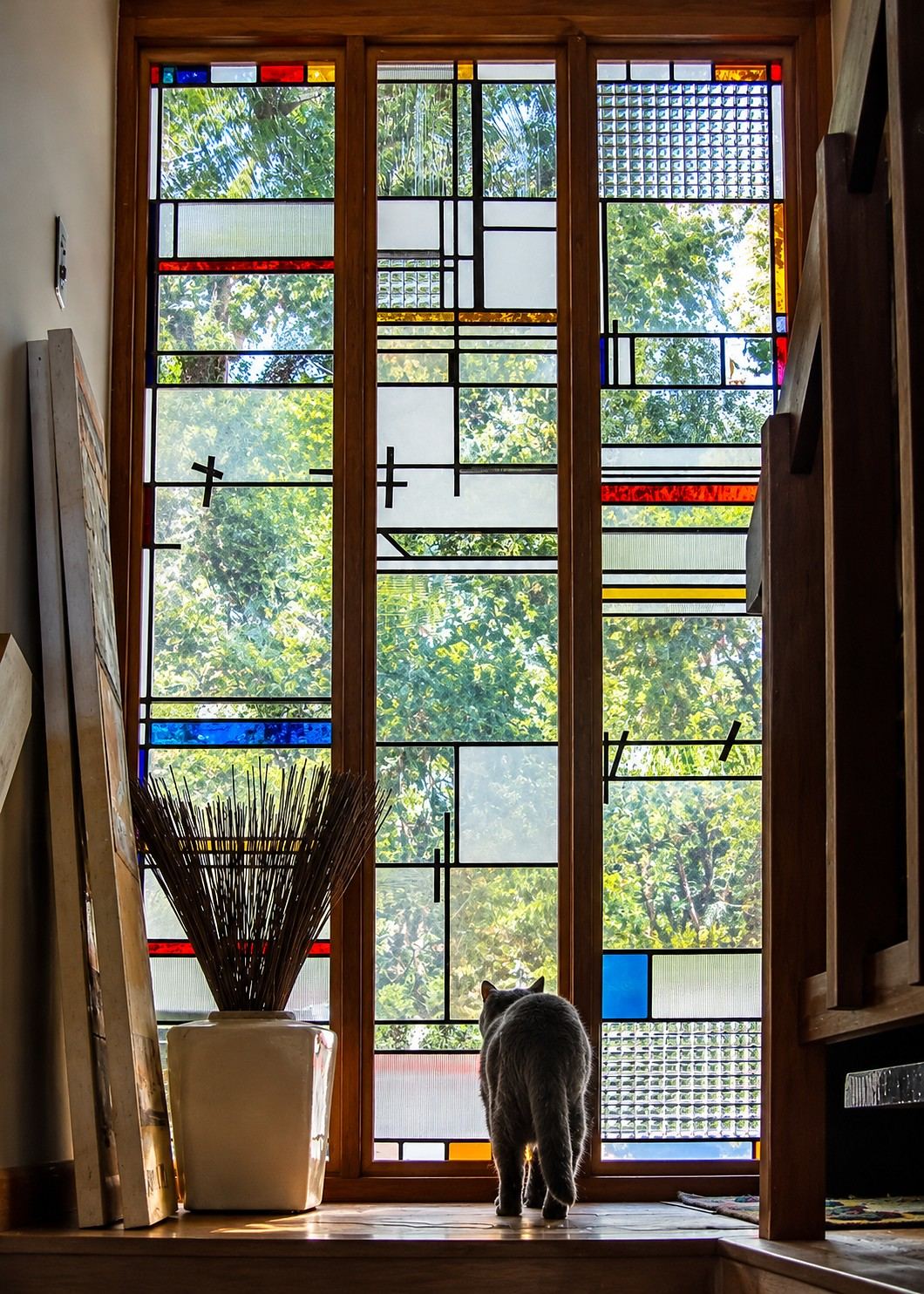 Contemporary stained glass sidelights in a Reston, Virginia residence, with geometric leaded design, handblown glass, colored accents and a cat looking toward the garden